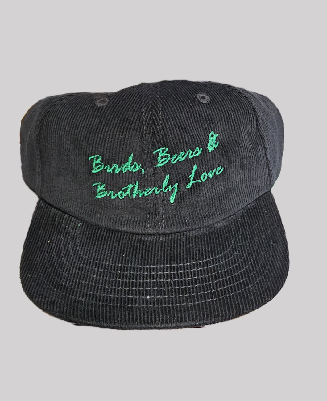 Black cap with green embroidered text on a gray background