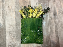 Green textured vase with flowers on a wooden surface