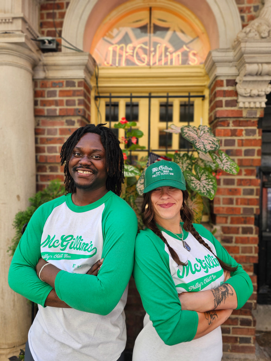 green and white baseball t-shirts with 'McGillin's' text on them, in front of pub entrance.