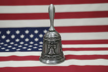 Silver bell with 'Independence' and 'Philadelphia' inscriptions on a beige background