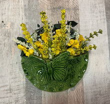 Decorative wallpocket with a butterfly design and yellow flowers on a wooden background