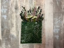 Green dragonfly-shaped planter with flowers on a wooden background