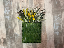 Green textured wall vase with flowers on a wooden background