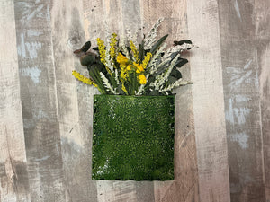 Green textured wall vase with flowers on a wooden background