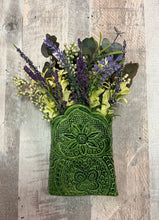 Green textured vase with a floral arrangement on a wooden surface